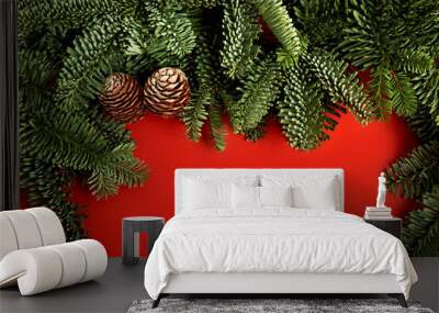 Festive red horizontal background with border from Christmas tree branches and cones.Copy space for text,new year natural layout. Wall mural