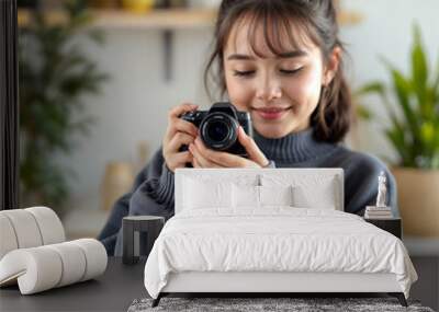 A young asian girl with long dark hair in a bun, wearing a gray sweater, holding a camera and smiling Wall mural