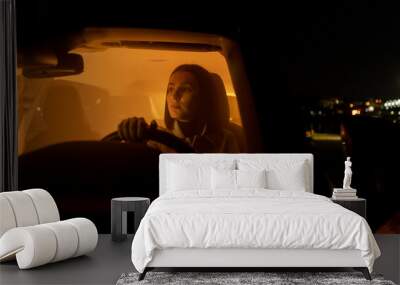 Serious relaxed woman enjoying night drive while sitting in car and looking away at driver seat Wall mural