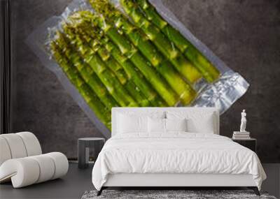 Hand holding asparagus over cooking pot Wall mural