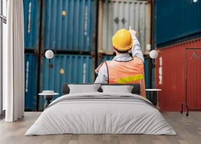 Asian technician dock worker in protective safety jumpsuit uniform and with hardhat and use laptop computer at cargo container shipping warehouse. transportation import,export logistic industrial Wall mural