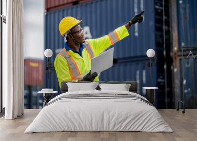 engineer man / worker in safety jumpsuit uniform with yellow hardhat and use laptop computer control at cargo container ship port warehouse.transport import,export logistic industrial service Wall mural