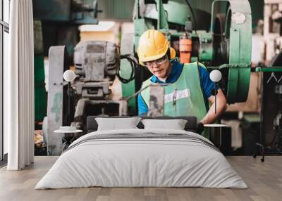 Work at factory.Asian worker man  working in safety work wear with yellow helmet using machine.in factory workshop industry meeting professional Wall mural