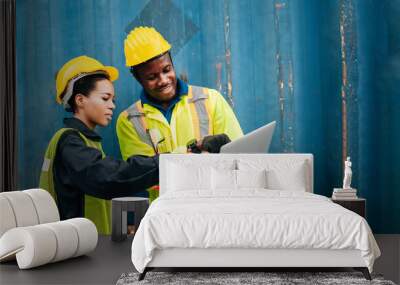 workers teamwork man and woman in safety jumpsuit uniform with yellow hardhat and use laptop check container at cargo shipping warehouse. transportation import,export logistic industrial service Wall mural