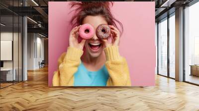 Young woman is smiling while she is watching through donuts on her eye. Donat is with pink chocolate dipping and colorful crumbles Wall mural