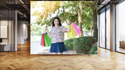 Asian woman shopping outside / Young lady woman happy smiley and holding colorful shopping bag in hand Wall mural