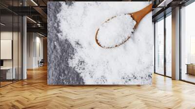 Salt in wooden spoon and heap of white salt on dark background top view Wall mural