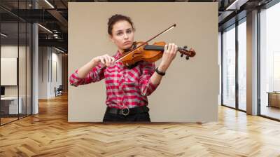 A photo of a young gir playing violin. Young violinist prepares for lesson. Wall mural