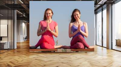 two adult women aged yoga outdoors in summer in the park Wall mural