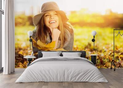 Happy young woman in park on sunny autumn day Wall mural