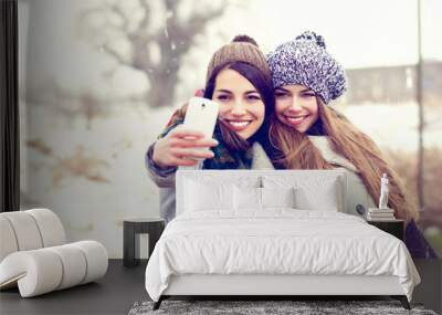 Two happy teenage girlfriends taking a selfie on snowy winter day Wall mural