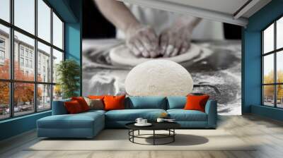 Ball of pizza dough on table with chef hands knead the dough in background. Wall mural