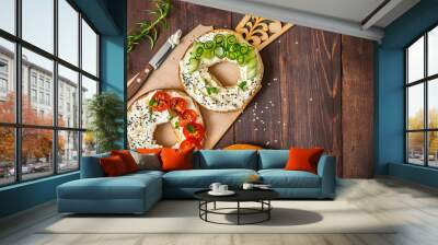 Bagels with cream cheese, sesame, tomato and cucumber on a wooden Board. Top view flat lay. With copy space Wall mural