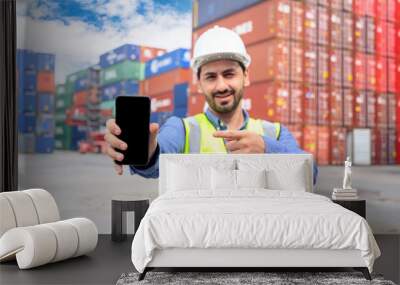 Logistic operators worker shows mock up mobile phone with blank screen, working in cargo container warehouse industry factory site in export, import, and transportation concept. Wall mural