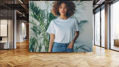 fashion photography of a model wearing an oversized white tshirt and jeans posing naturally in a minimalist interior with a large potted plant emphasizing the shirts relaxed fit Wall mural