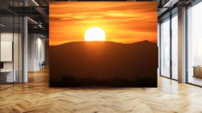 Beautiful evening panoramic landscape with bright setting sun over distant mountain peaks at sunset Wall mural