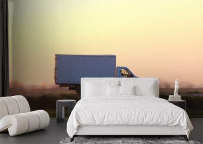 Cargo truck driving on highway hauling goods in evening. Delivery transportation and logistics concept Wall mural