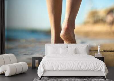 Close up of woman feet walking barefoot on sand beach in sea water. Vacation, travel and freedom concept. People relaxing in summer. Wall mural