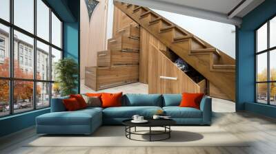 Modern architecture interior with luxury hallway with glossy wooden stairs in multi-storey house. Custom built pullout cabinets on glides in slots under stairs. Use of space for storage. Wall mural