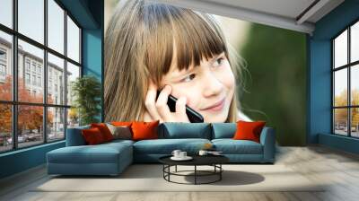 Portrait of pretty child girl with long hair talking on cell phone. Little female kid communicating using smartphone. Children communication concept. Wall mural