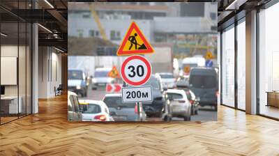 Roadworks warning traffic signs of construction work on city street and slowly moving cars Wall mural