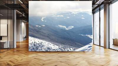 Silhouette of alone tourist standing on snowy mountain top in winner pose with raised hands enjoying view and achievement on bright sunny winter day. Adventure, outdoors activities, healthy lifestyle. Wall mural