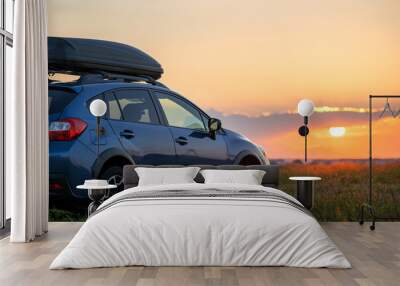 SUV car with roof rack luggage container for off road travelling parked at roadside at sunset. Road trip and getaway concept. Wall mural