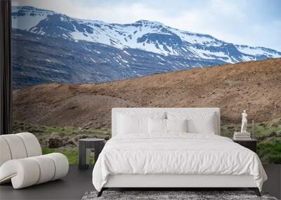 Snow mountain range at Seydisfjordur, Iceland with meadow and sand mountain in front Wall mural