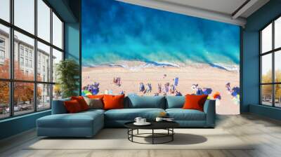 Aerial view on the beach, people and umbrellas. Vacation and adventure. Beach and blue water. Top view from drone at beach and azure sea. View on the coast from drone. Wall mural