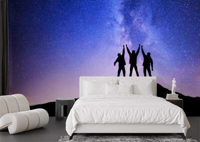 Silhouettes of team on mountain peak. Sport and active life concept on the night sky background. Wall mural