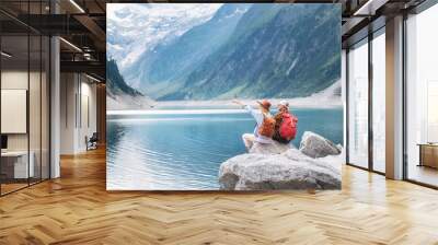 Travelers couple look at the mountain lake. Travel and active life concept with team. Adventure and travel in the mountains region in the Austria Wall mural