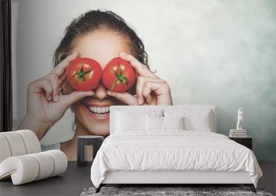 Beautiful laughing woman holding two ripe tomatoes Wall mural