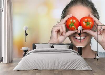 Beautiful laughing woman holding two ripe tomatoes Wall mural