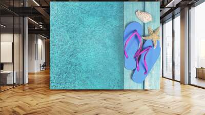 Colored flip flops sitting on the edge of a swimming pool. Wall mural