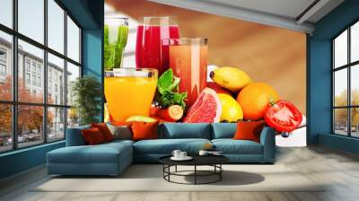 Composition of fruits and glasses of juice on blurred natural background Wall mural