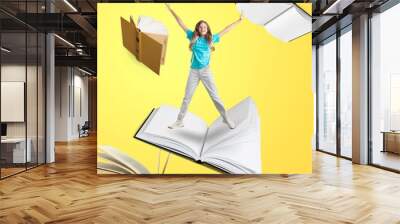 Contemporary art collage of child, girl flying, surfing on open book on yellow background. Concept of artwork education Wall mural