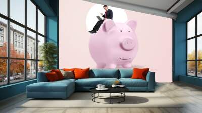 Digital technologies banking sector. Business man on huge piggy bank Wall mural