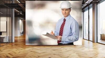 Engineer taking a note. Focused man in white hardhat holding a clipboard and writing. Waist up studio shot isolated on white. Wall mural