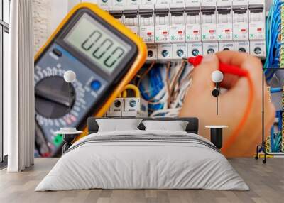 Hand of an electrician with multimeter probe at an electrical Wall mural