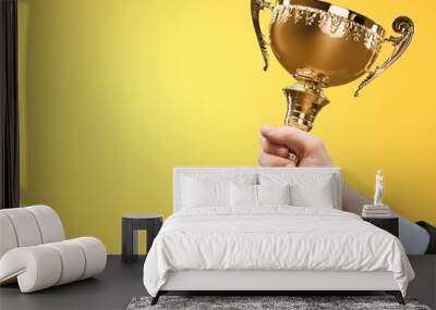 Hands holding golden trophy on light background Wall mural