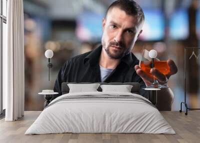 Handsome man with a glass of alcohol in bar Wall mural