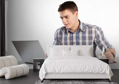 Happy young man works on his laptop with coffee at the table Wall mural