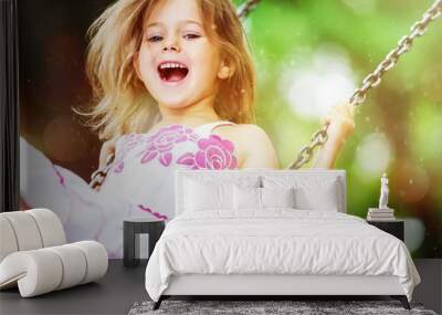 Little child blond girl having fun on a swing Wall mural