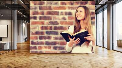 Man holding old bible book on brick wall background Wall mural