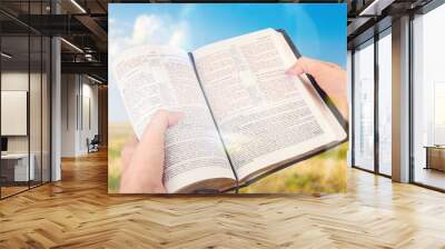 Open bible book in hands at wheat field Wall mural