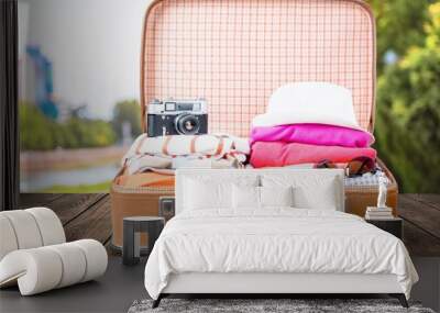 Retro luggage with colorful clothes on blurred background Wall mural