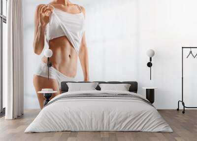 Slim woman doing fitness workout, standing in activewear with abs and muscles Wall mural