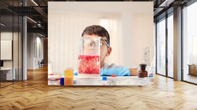 Smart boy during scientific chemistry experiment wearing protection glasses, holding bottle with liquid. chemical equipment on school lesson portrait Wall mural