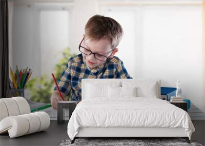 Smiling intelligent schooler teen doing homework, sitting at table, enjoying educational process Wall mural