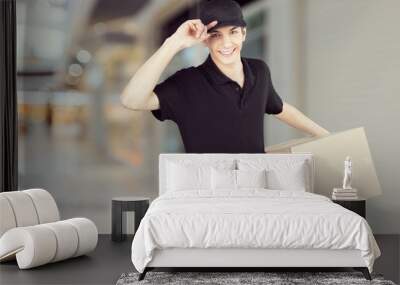 Smiling young man delivering box Wall mural